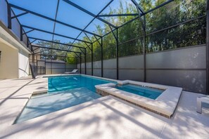 Ein Schwimmbad mit Glasveranda, eine Whirlwanne und eine Sonnenliege.