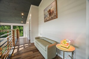 Een modern interieur met een houten vloer, een groene bank, een ronde tafel met een lamp en een schilderij van een jak.