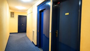Ein Flur mit einer blauen Tür, auf der 'PRIVATE' steht, und einem Lüftungsgitter an der Wand.