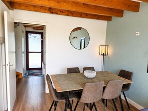 Un comedor con una mesa de madera, seis sillas, un espejo redondo y una lámpara de pie.