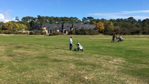 En golfbane med en klubhus i baggrunden.