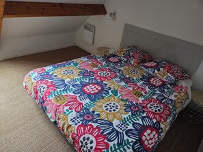 Een slaapkamer met een bloemenprint bedsprei, een hoofdbord en een vloerbedekking.
