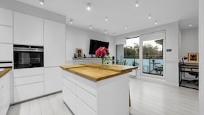 A modern kitchen with white cabinetry, a wooden countertop, and a built-in oven.
