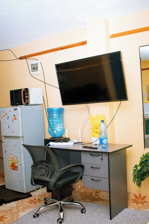 A small office space with a desk, chair, refrigerator, microwave, water dispenser, and a flat-screen TV mounted on the wall. - Modern & Cozy Stay in isiolo 
and 
 Archer's Post in samburu county (Isiolo)