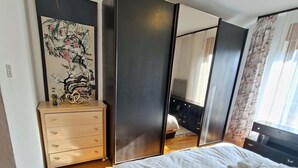 Um quarto com uma cama, cômoda, espelho e um quadro na parede.
