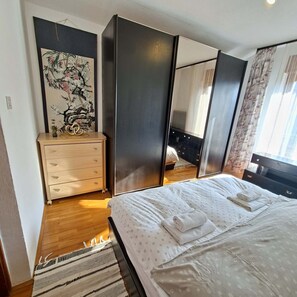 Un dormitorio con cama, cómoda, espejo y un cuadro en la pared.