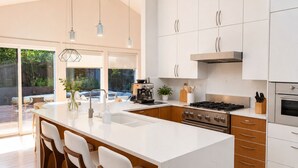 Een moderne keuken met een groot eiland, roestvrijstalen apparatuur en uitzicht op de omgeving.
