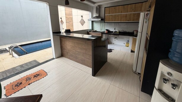 A modern kitchen with a central island, wooden cabinets, a built-in oven, and a water dispenser. - Rooms for rent in Belém (Belém)