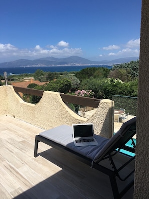 A balcony with a laptop, lounge chairs, and a view of the sea and mountains. - Beautiful duplex 300 m from the beach, private pool, petanque,... (Pietrosella)