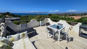 Una terraza en la azotea con mesa y sillas, un sofá y vistas al mar y a las montañas.