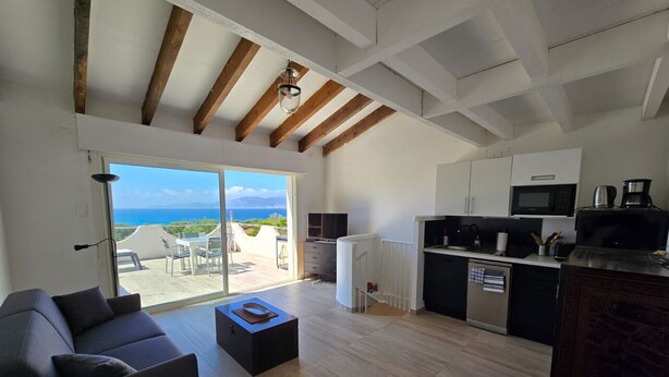 Una sala de estar moderna con un sofá, una mesa de centro y vistas al mar a través de amplios ventanales.