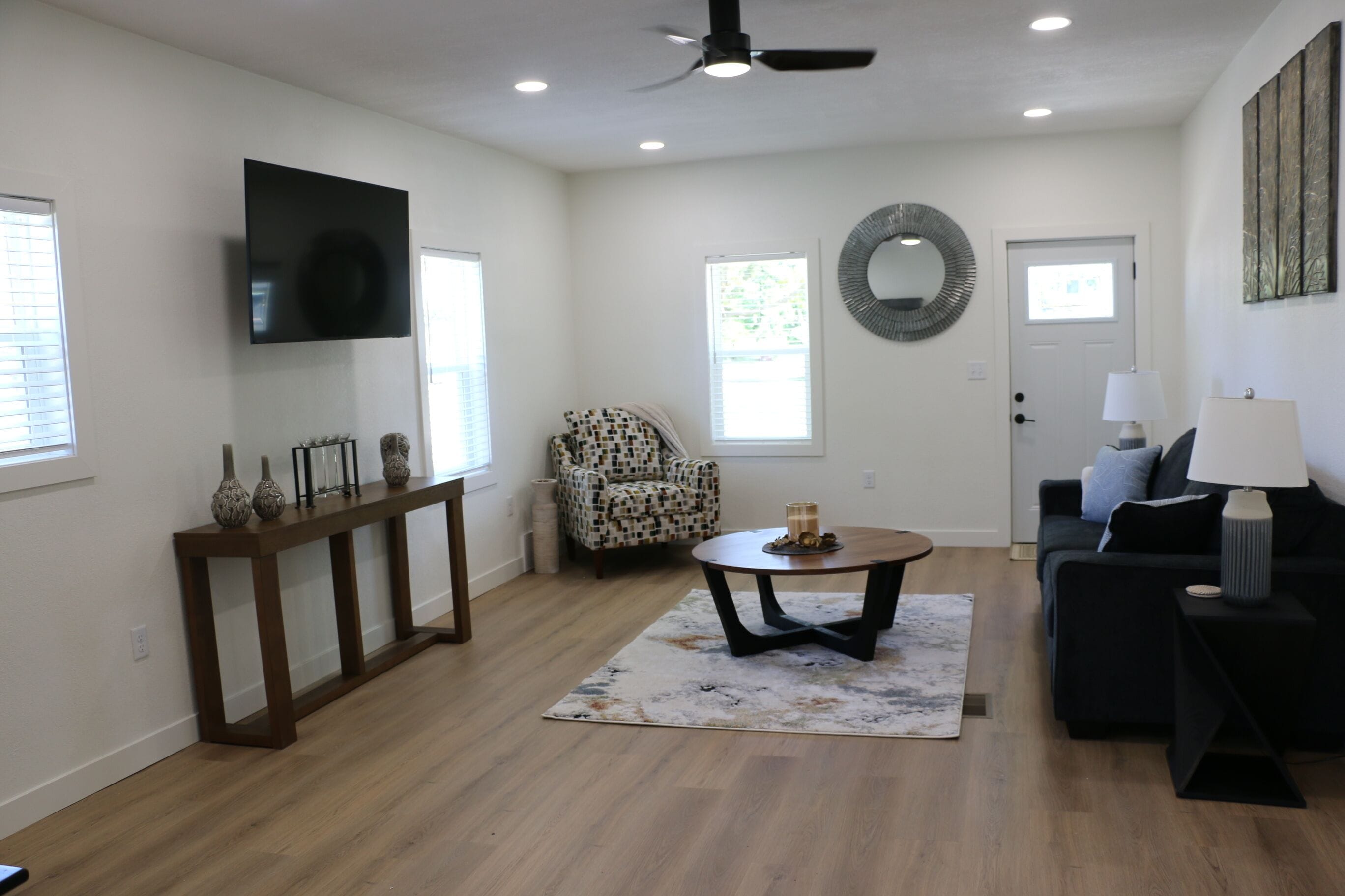 A living room with a TV, a round mirror, a patterned armchair, a coffee table, and a sofa.. Home in Fredericksburg, IA--Newly Renovated!
