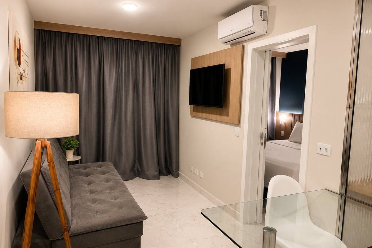 A modern living room with a sofa, a glass table, a lamp, a TV, and an air conditioning unit.
