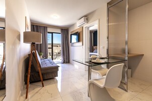 Una habitación de hotel moderna con una mesa de comedor de vidrio, un sofá, una lámpara y un televisor.