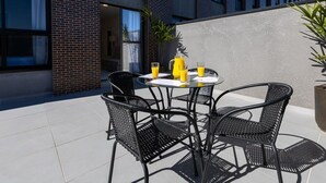Een terras met een tafel en stoelen, een potplant en een gebouw op de achtergrond.