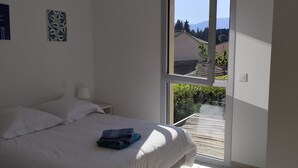 Un dormitorio con cama, ventana y vistas al exterior.