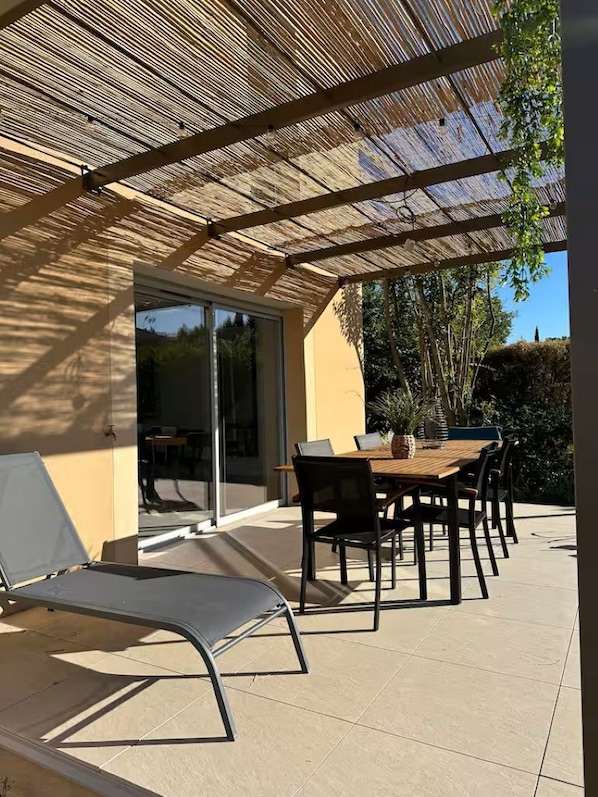 A covered patio with a table and chairs, a sliding glass door, and a view of the outdoors. - LE SOLEIL DU GOLF PMR Sud (Saumane-de-Vaucluse)