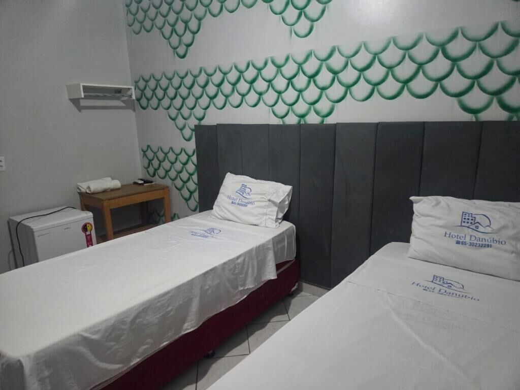Habitación de hotel con dos camas, una mesita, una mesita de noche y una pared con un diseño de escamas de pez verde.