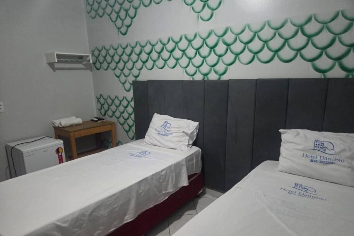 Habitación de hotel con dos camas, una mesita, una mesita de noche y una pared con un diseño de escamas de pez verde.