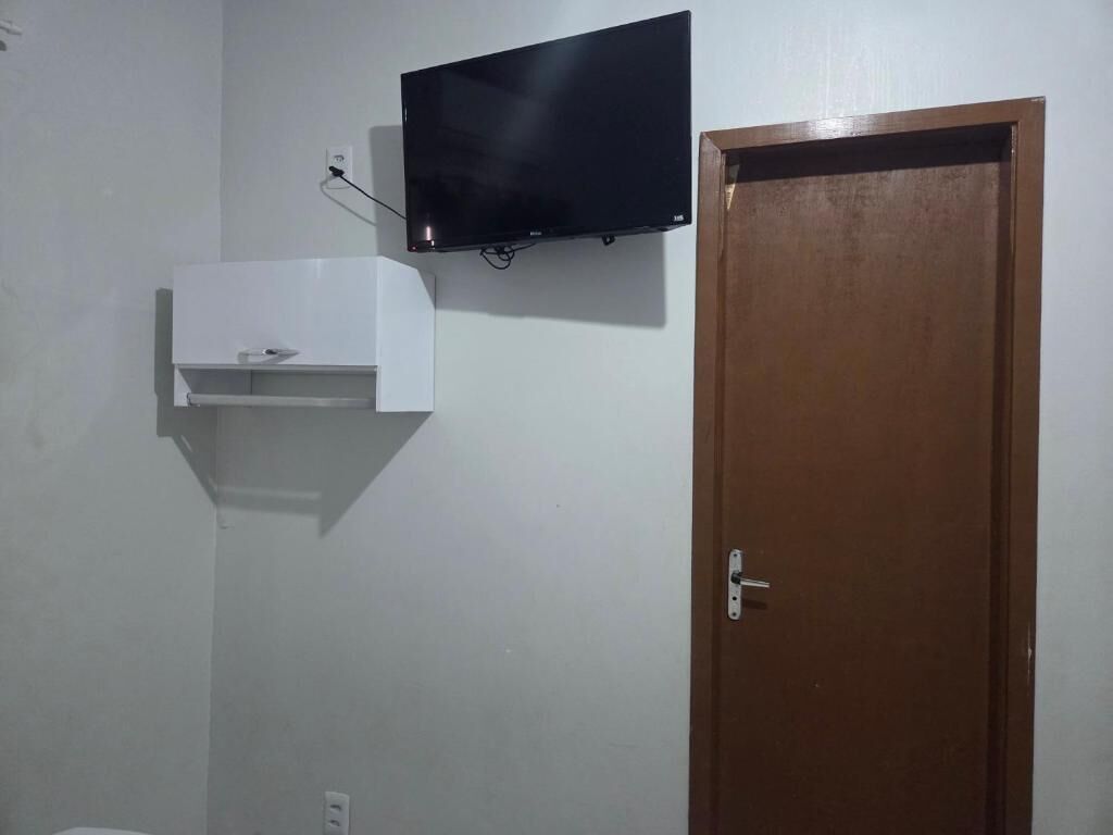A room with a mounted television, a white cabinet, and a wooden door.