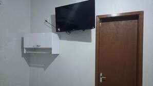 Una habitación con televisión montada, un armario blanco y una puerta de madera.