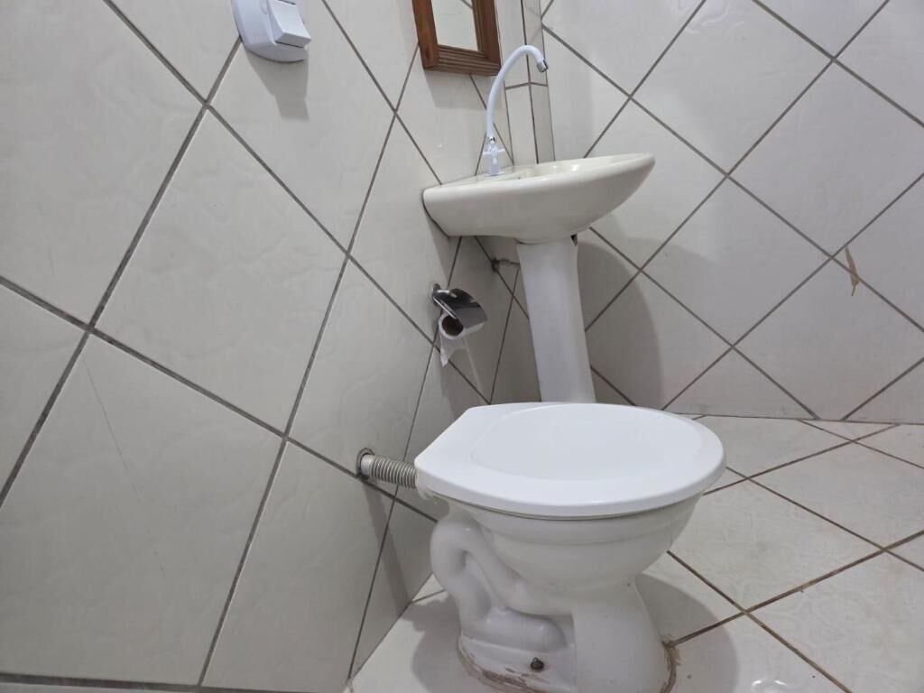 Un baño con inodoro blanco, lavamanos pedestal y espejo montado en la pared.
