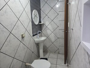 Un baño con lavamanos blanco, inodoro y espejo.