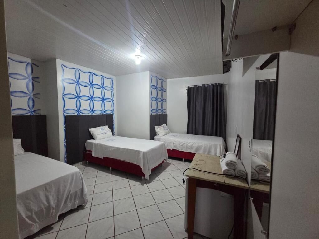 Habitación de hotel con dos camas individuales, una mesita con toallas, un espejo y un diseño de pared estampado.