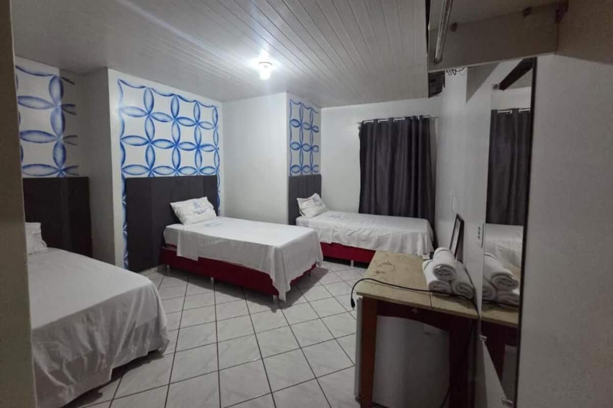Habitación de hotel con dos camas individuales, una mesita con toallas, un espejo y un diseño de pared estampado.