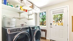 A laundry area with two front-loading washers, a basket, and shelves with various items. - 4BR Wellness Retreat Hot Tub, Sauna & Game Room (Nekoosa)