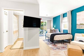 Een slaapkamer met een bed, een televisie, een raam met gordijnen en uitzicht op het omliggende landschap.