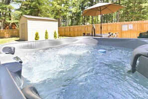 Een hottub met een houten terras, een kleine schuur en een houten hek.