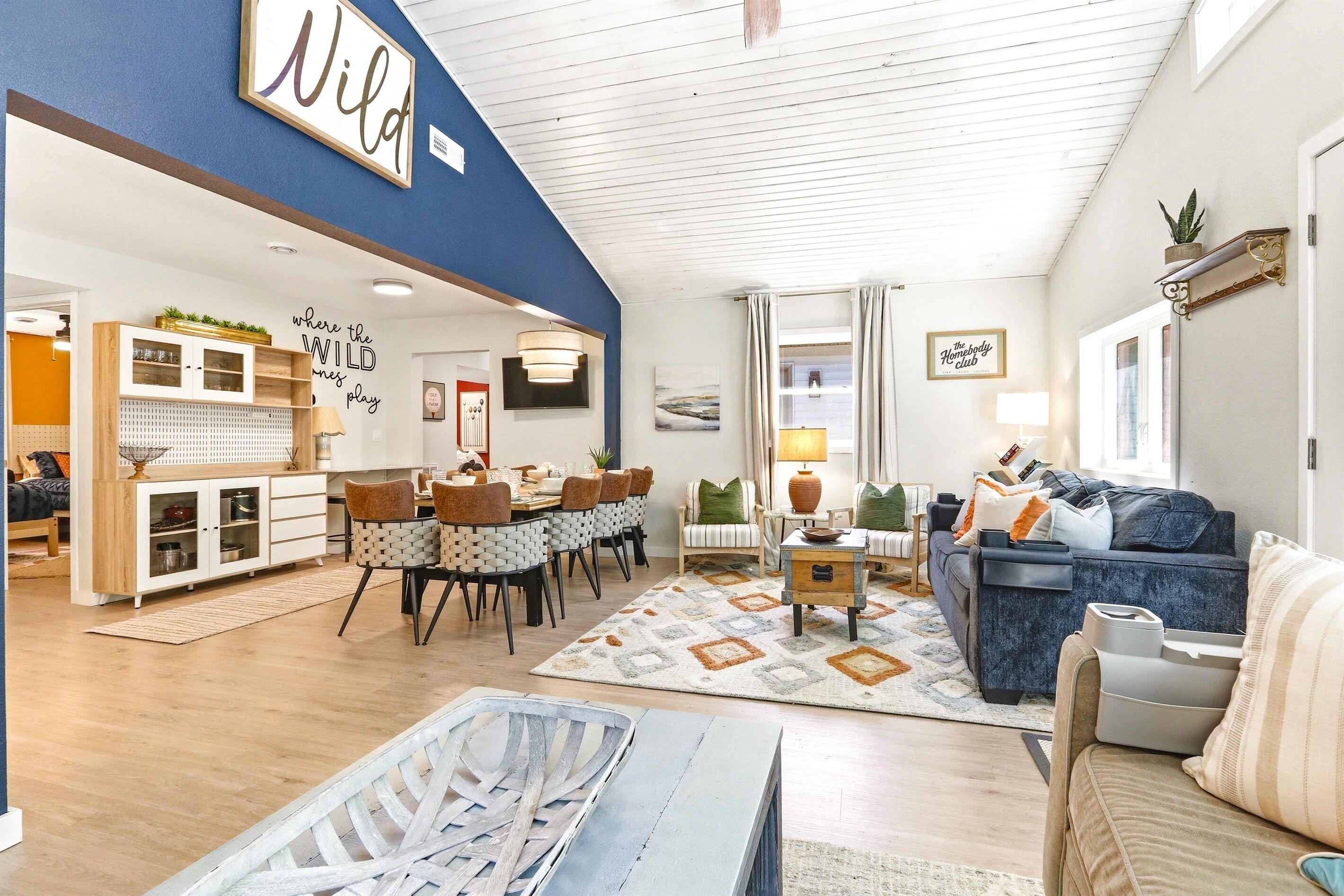 A spacious living area with a dining set, a sofa, and a large wall sign.