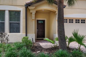 Ein Haus mit einer dunkelbraunen Tür, beige gefärbten Wänden und einer Garage.