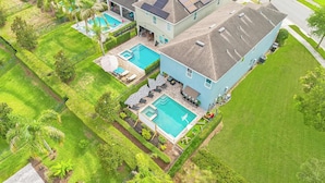 Propiedad residencial con dos piscinas, un porche cubierto y un jardín ajardinado.