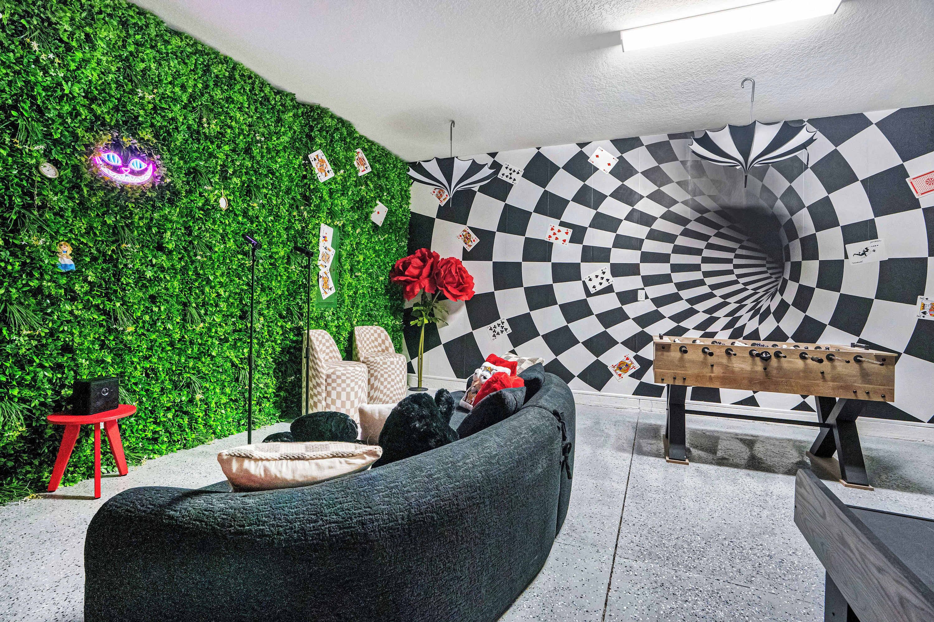 A room with a green wall, a checkered wall design, a sofa, a red chair, and a wooden bench.
