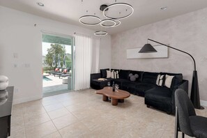 En moderne stue med en hjørnesofa, sofabord og en hængende lampe.