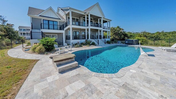 Une grande maison avec une piscine, du mobilier d’extérieur et un jardin bien entretenu.