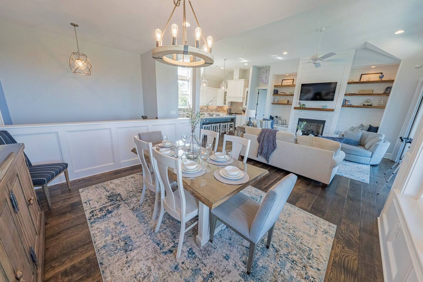 A spacious living area with a dining table set for four, a kitchen in the background, and a fireplace.