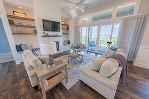 Ein geräumiges Wohnzimmer mit Kamin, Fernseher und einem Balkon mit Blick.
