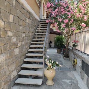 Eine Treppe führt zu einem Balkon mit einem Blumentopf und einer Blumenvase.