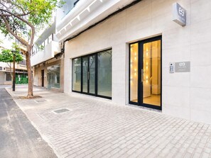 Ein modernes Gebäude mit Glasfenstern und -türen, einem gepflasterten Gehweg und einem Baum.
