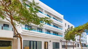 Un hôtel à plusieurs étages, doté d’une façade blanche, de touches de couleur bleue et de grandes fenêtres.