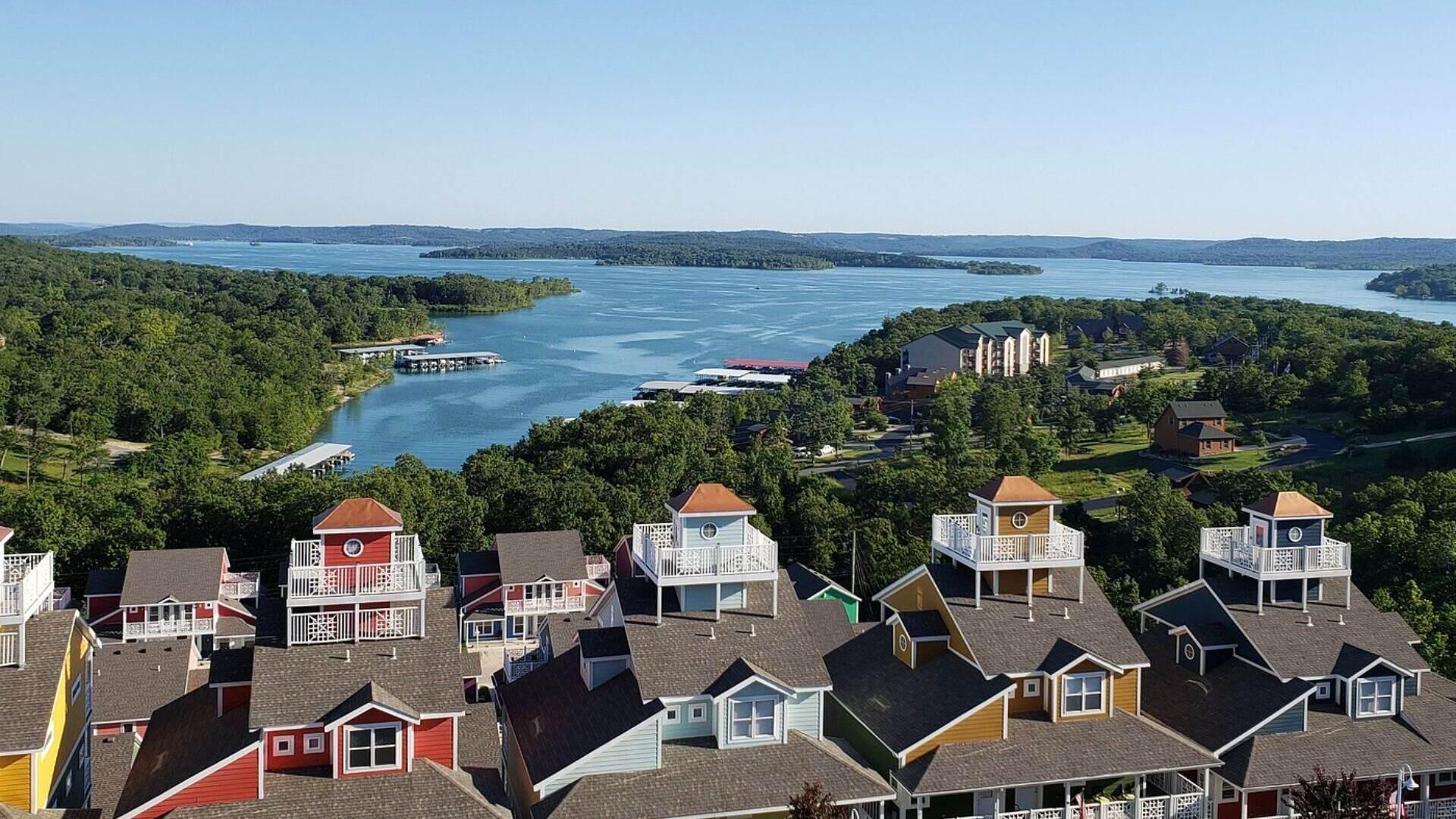 Un quartier résidentiel avec des maisons dotées de balcons, un lac et une rive éloignée.