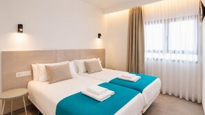 Ein Hotelzimmer mit zwei Betten, einem kleinen Tisch und einem Fernseher.