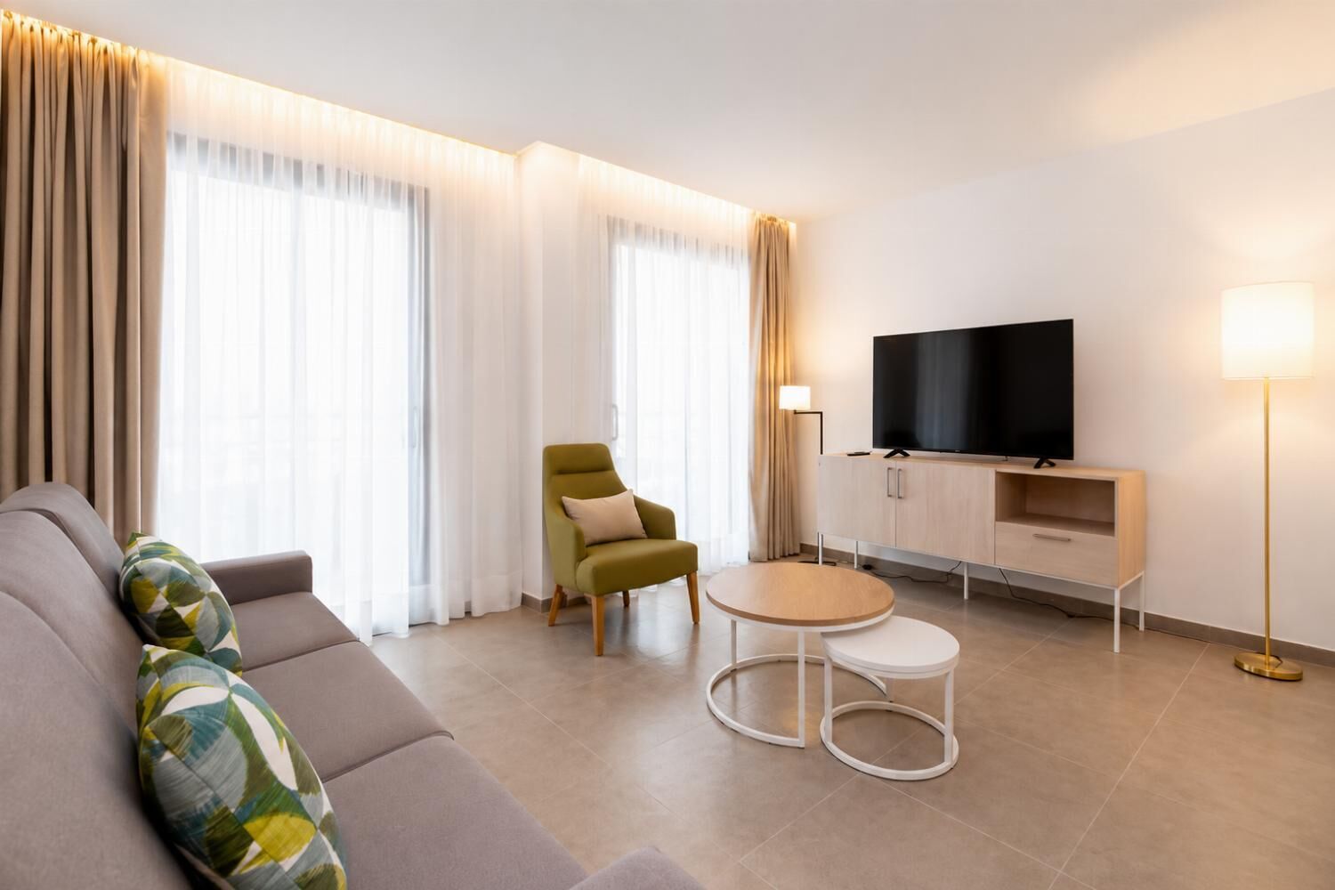Een moderne woonkamer met een bank, fauteuil, televisie en een salontafel.