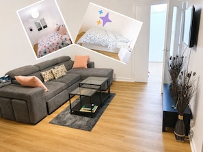 Ein Wohnzimmer mit einem grauen Ecksofa, einem Glastisch und einem grauen Teppich.