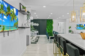 A modern kitchen with a white countertop, bar stools, and a green vertical garden wall.