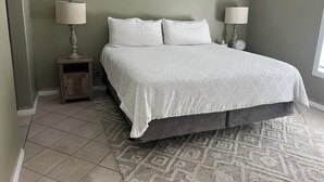 A bedroom with a bed, two bedside lamps, a nightstand, and a patterned rug. - Cozy 1-bedroom house in superb Valley Center with AC (Valley Center)