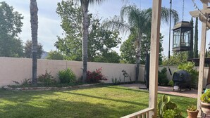 A backyard with a lawn, potted plants, a wooden deck, and a barbecue grill. - Cozy 1-bedroom house in superb Valley Center with AC (Valley Center)